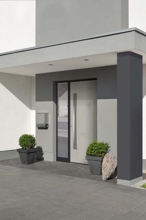Moderner Hauseingang mit heller Haustür und Glasseitenteil, minimalistischer Gestaltung und stilvoller Begrünung in Pflanzkübeln.