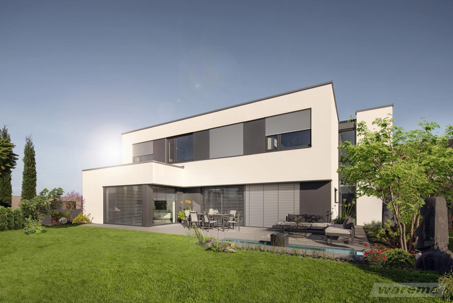 Das Bild zeigt ein modernes Flachdachhaus mit großen Fensterflächen und außenliegenden Rollläden und Raffstores, umgeben von einem gepflegten Garten.